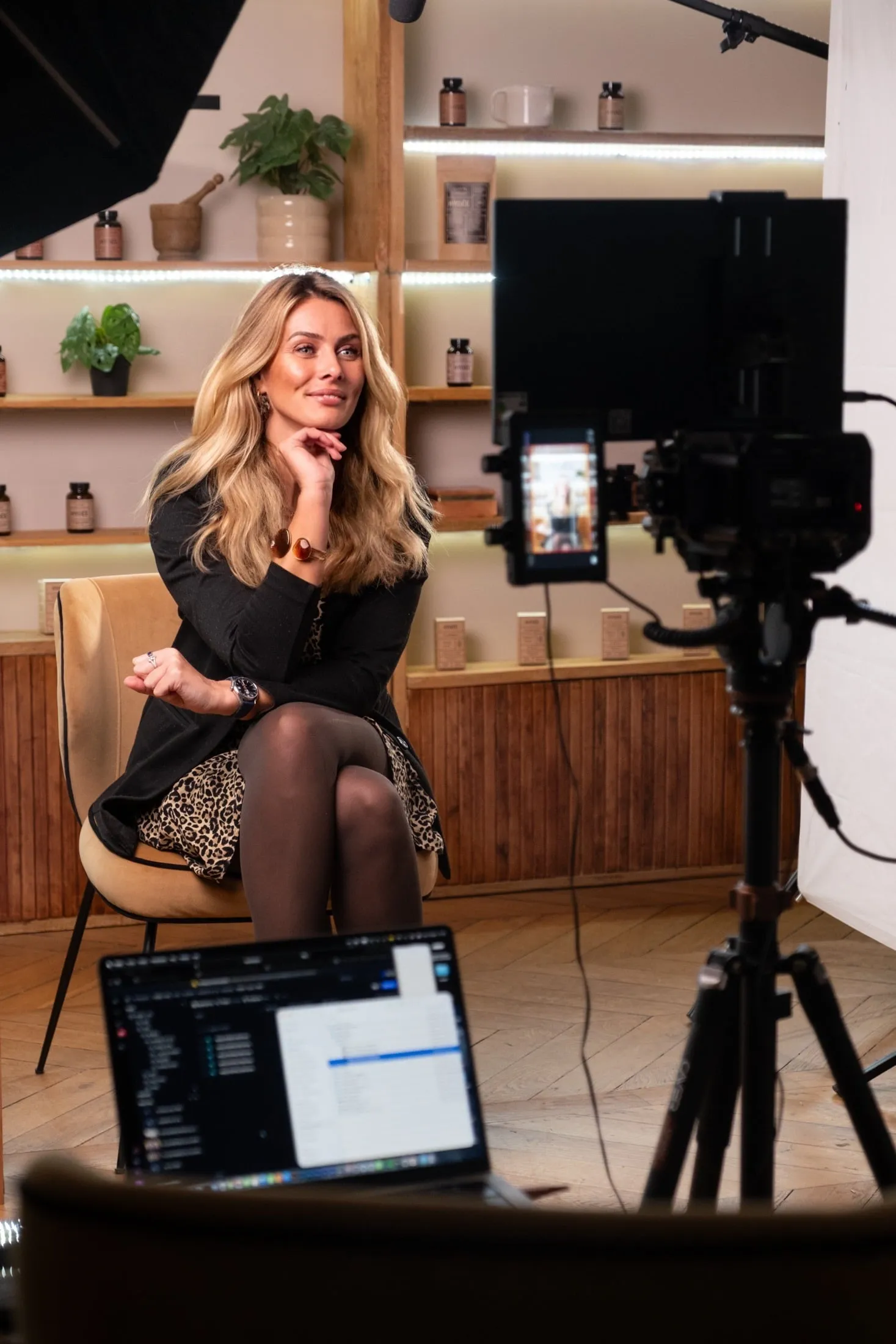 Mélanie en plein tournage : smartphone sur trépied, éclairage studio, étagères de produits soin